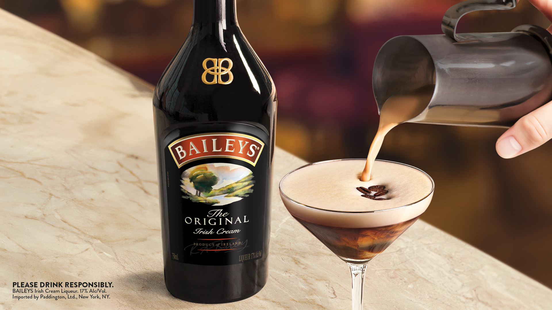 Pouring a Baileys Espresso Martini into a glass, with a bottle of Baileys to the left