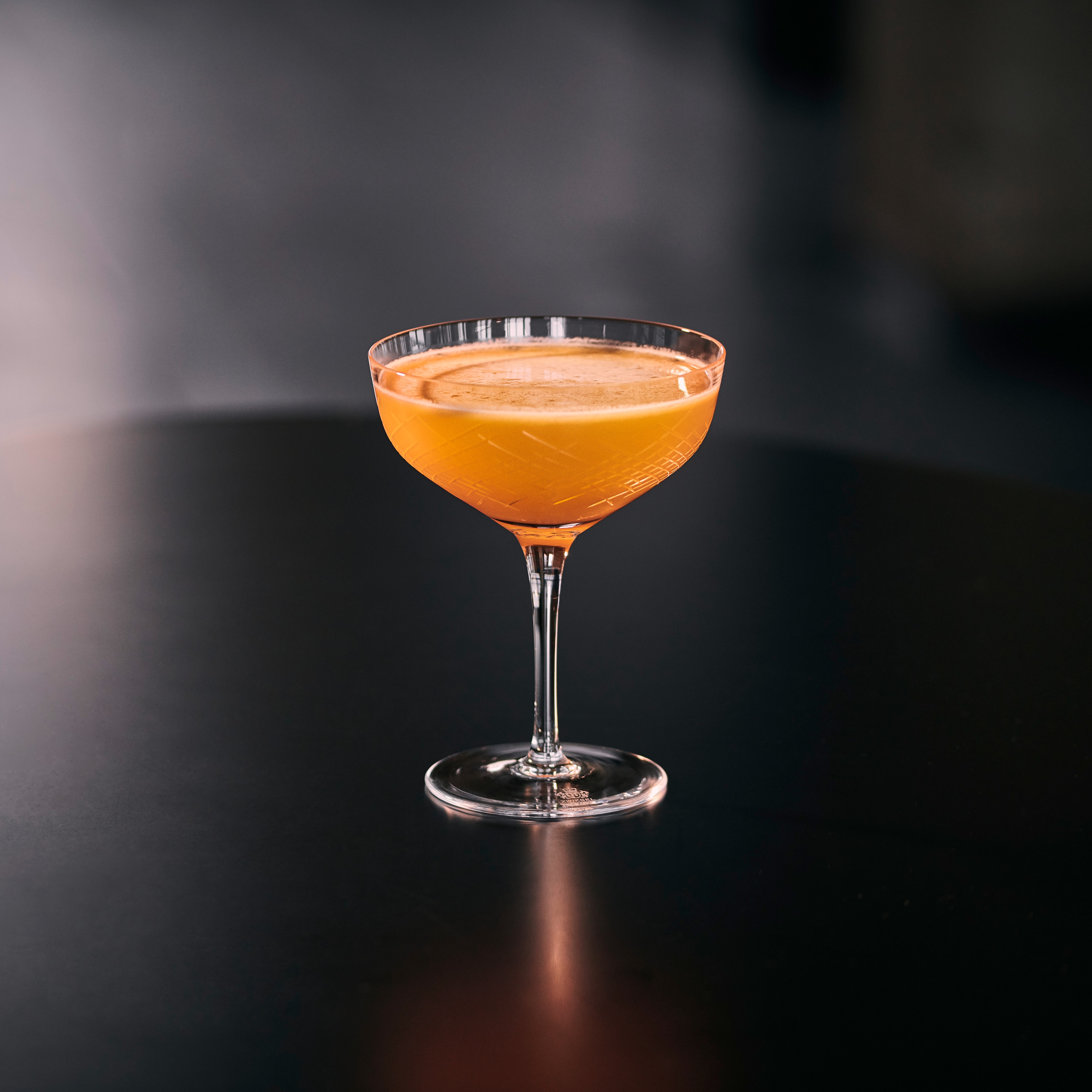 A Tequila Martini cocktail on a shiny black table. 