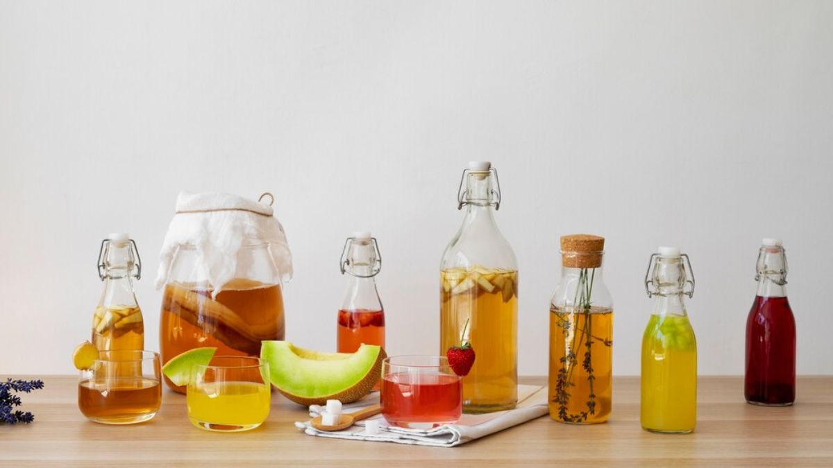 A selection of jars, fruits and utensils laid out on a kitchen tabletop, in the process of making homemade syrups