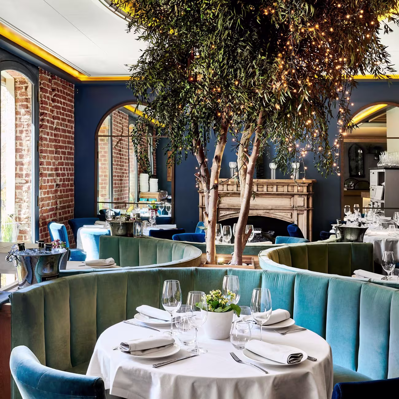 Ambiente sofisticado de Ten con Ten, con muros de ladrillo visto, asientos de terciopelo azul y detalles decorativos que irradian elegancia.