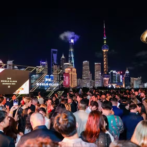 En la imagen se ve una multitud de gente, con el cartel de World Calss y el paisaje de Shanghai de fondo.
