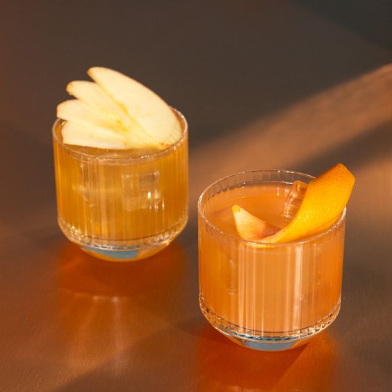 Dos vasos de whisky con cáscara de naranja