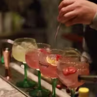 La imagen muestra diferentes copas rellenas con cócteles preparados con gin Tanqueray sobre una barra de tragos.