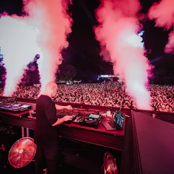 La imagen muestra la fiesta "Music On", con un DJ y un grupo grande de personas.
