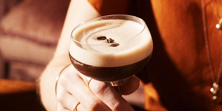 Primer plano de un Espresso Martini en una copa coupé, en un ambiente íntimo y cálidamente iluminado.