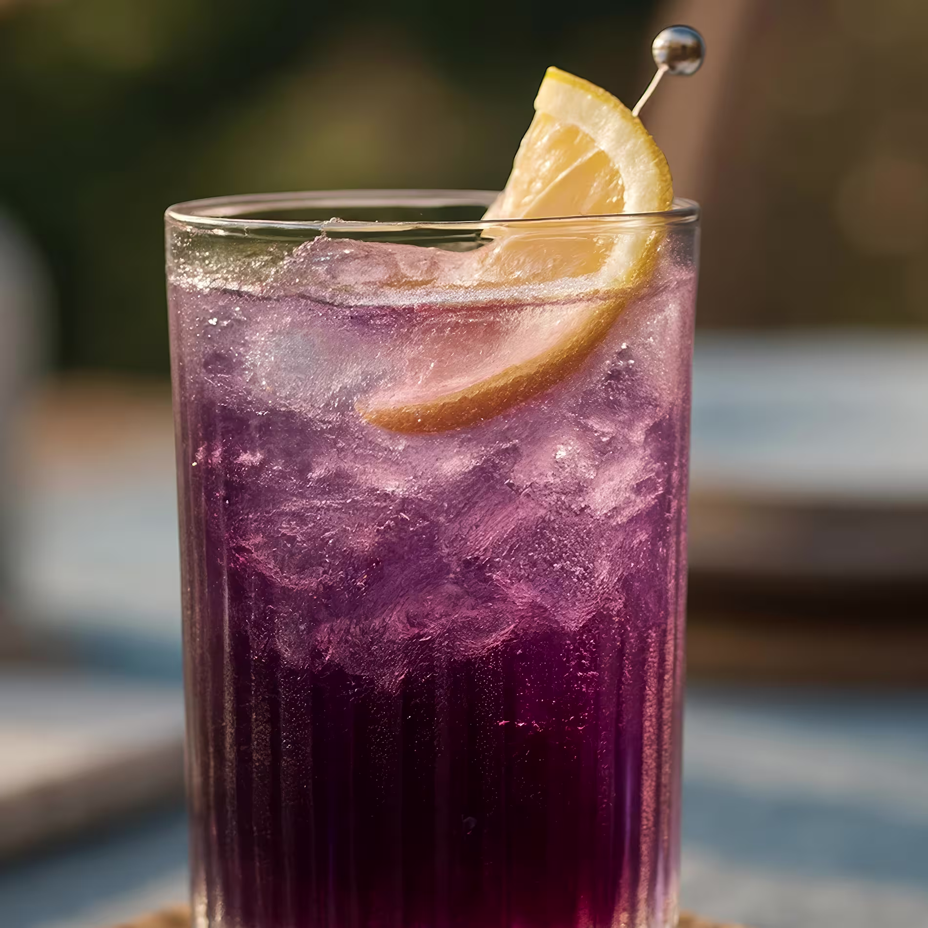 Lila koktél nyársra tűzött citromkerékkel díszítve