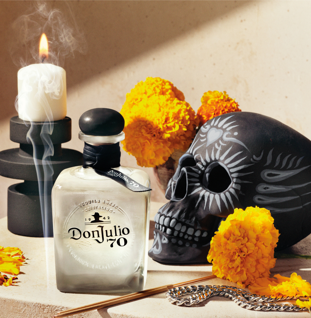 Botella de Don Julio 70 junto a una calavera y flores de cempasúchil
