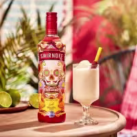La imagen muestra una botella de Smirnoff Spicy Tamarind junto a una copa rellena con un cóctel preparado con dicho destilado.