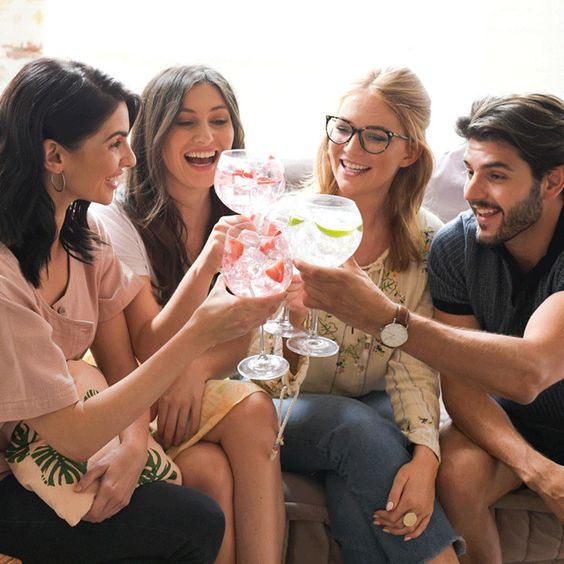 La imagen muestra a un grupo de amigos, cada uno con una copa con cóctel en la mano.
