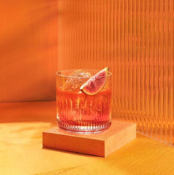  Black Boulevardier in a Whisky Glass on a table with an orange background 