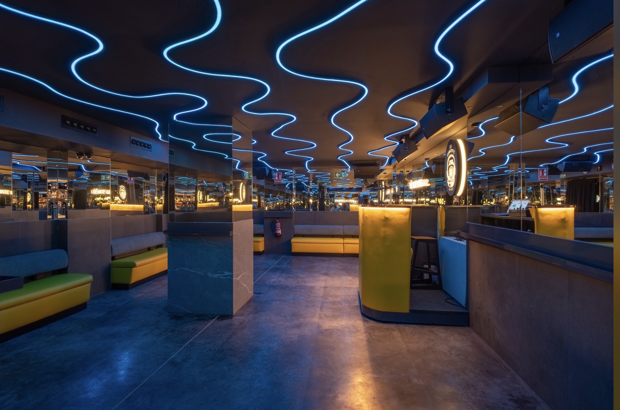 Interior de La Corriente del Golfo, con un diseño moderno y techos iluminados por neones azules ondulados, creando un ambiente vibrante y futurista.