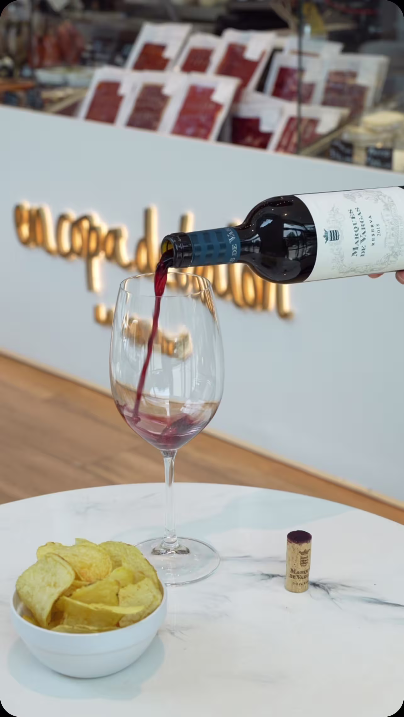 Copa de vino tinto servido en En Copa de Balón, acompañado de crujientes patatas en un ambiente sofisticado y acogedor.