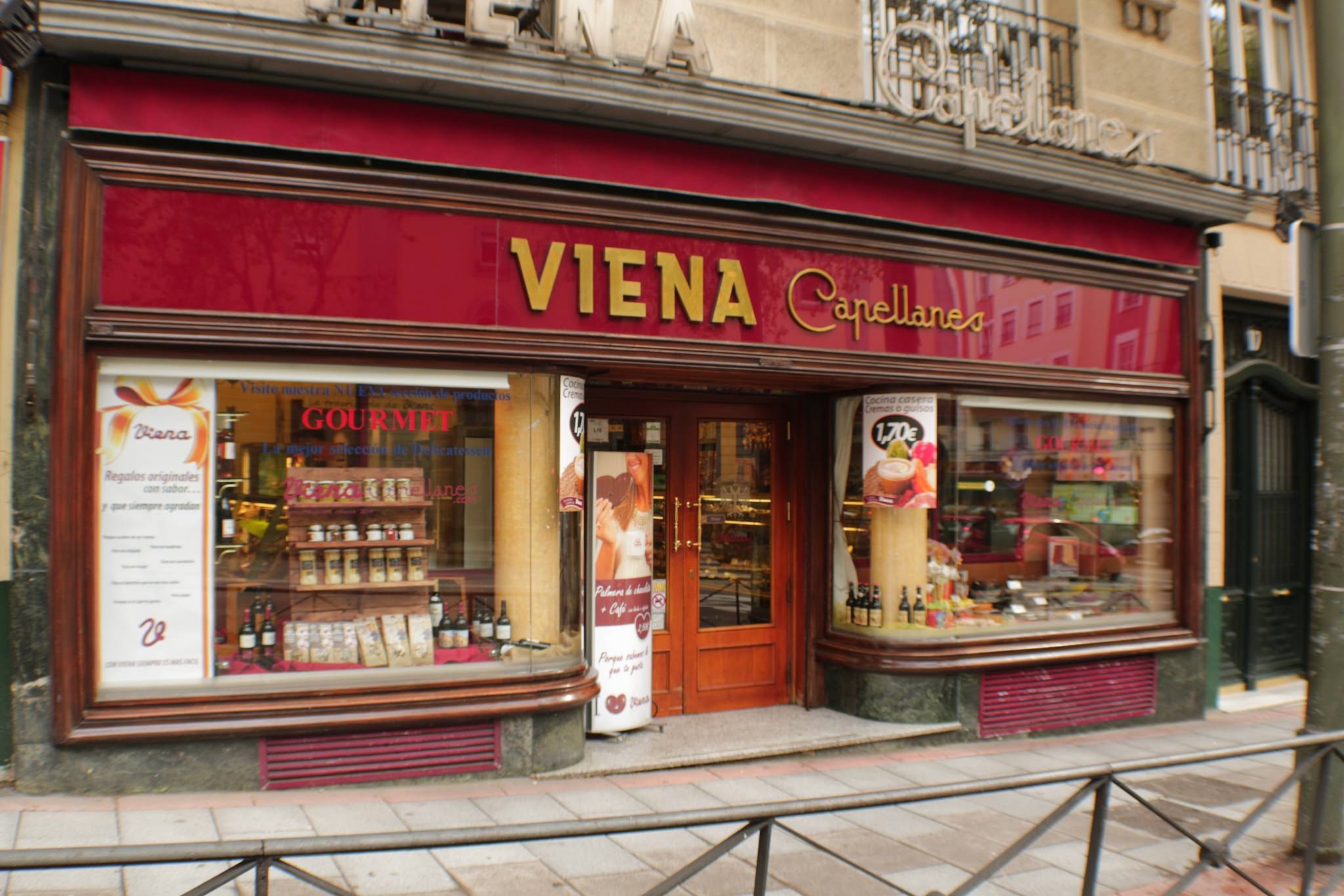 Fachada en tonos burdeos y escaparates gourmet en Viena Capellanes Argüelles. Un local con esencia clásica y sabor tradicional.