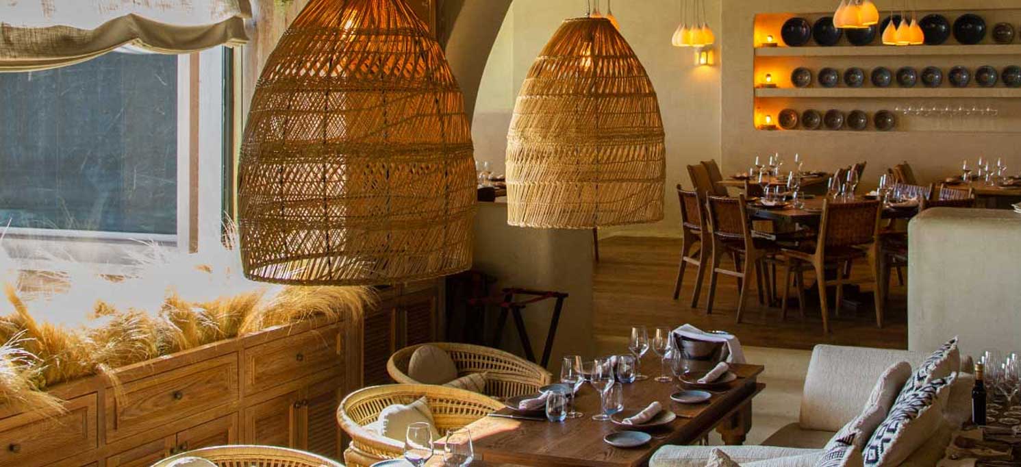 A Brasa Moraleja presenta un ambiente cálido y natural con mobiliario de madera, lámparas y detalles acogedores, ideal para una experiencia relajada.