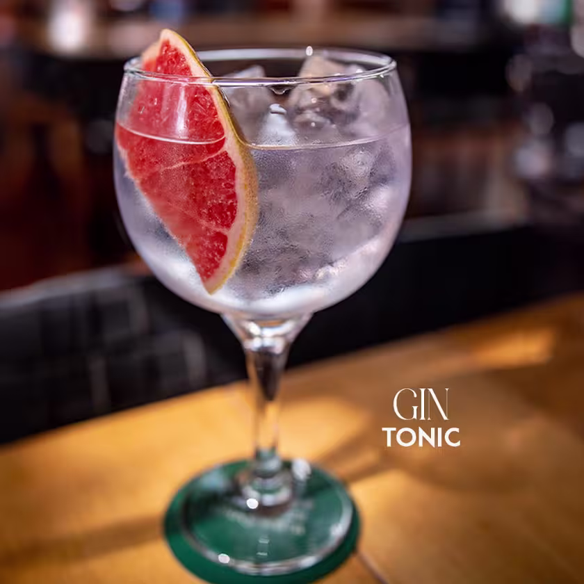 una copa de gin tonic con una rodaja de pomelo.