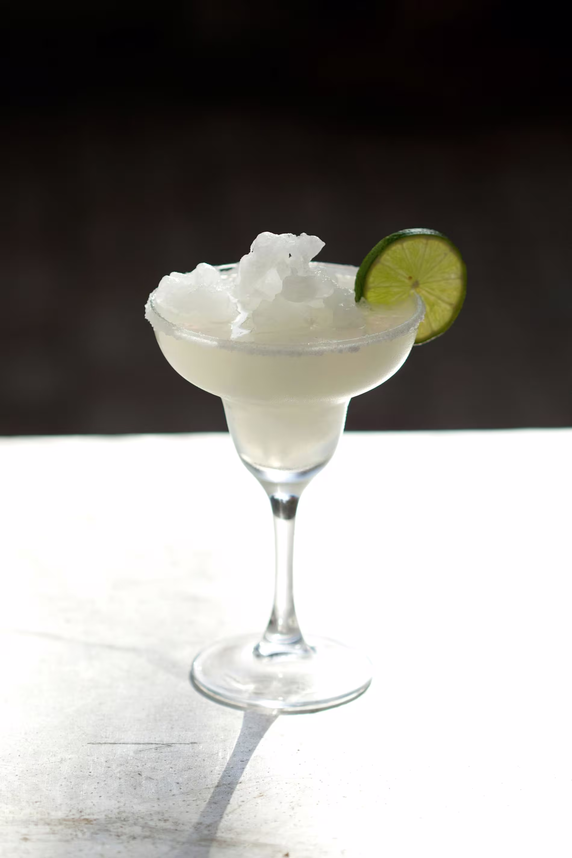 A classic margarita served in a stemmed glass, topped with crushed ice and garnished with a lime wheel.