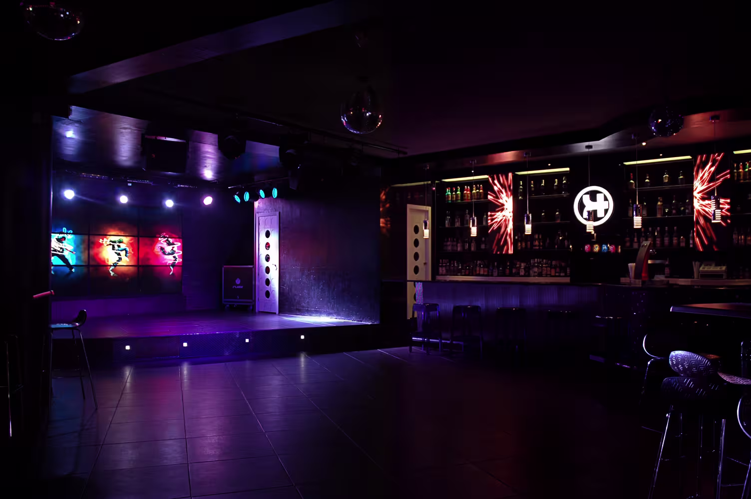 Interior de Sala Silikona con escenario iluminado y barra moderna. Ambiente de conciertos con luces vibrantes y espacio para el público.