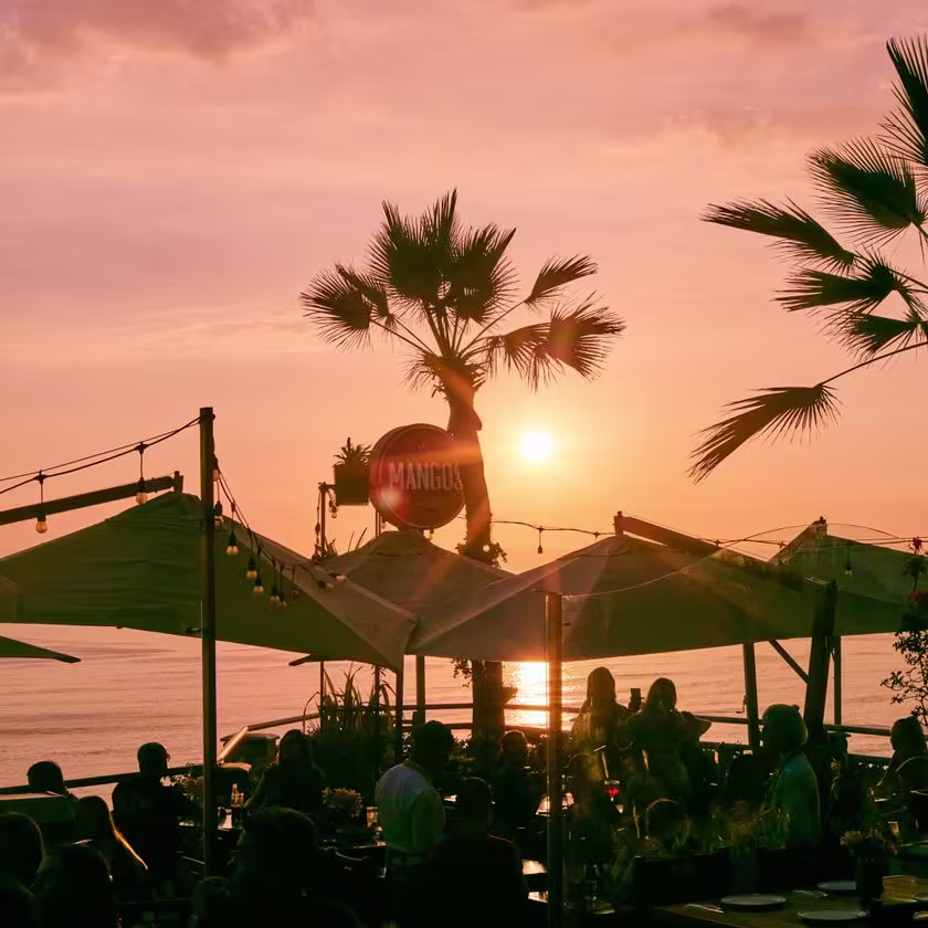 Foto de atardecer. en contraste las sombrillas y mesas del lugar.