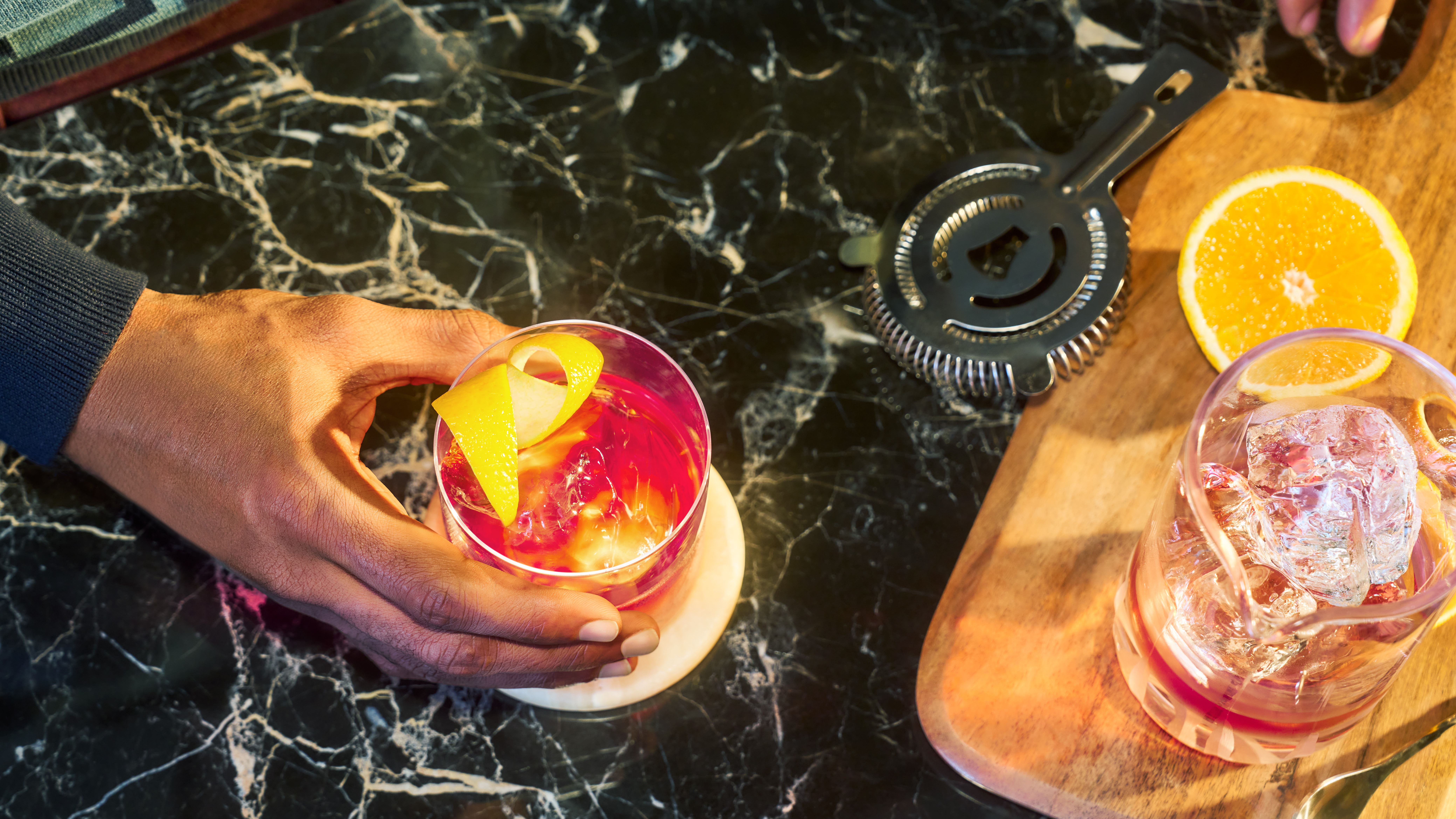 A negroni cocktail on a marbled kitchen counter, seen from above