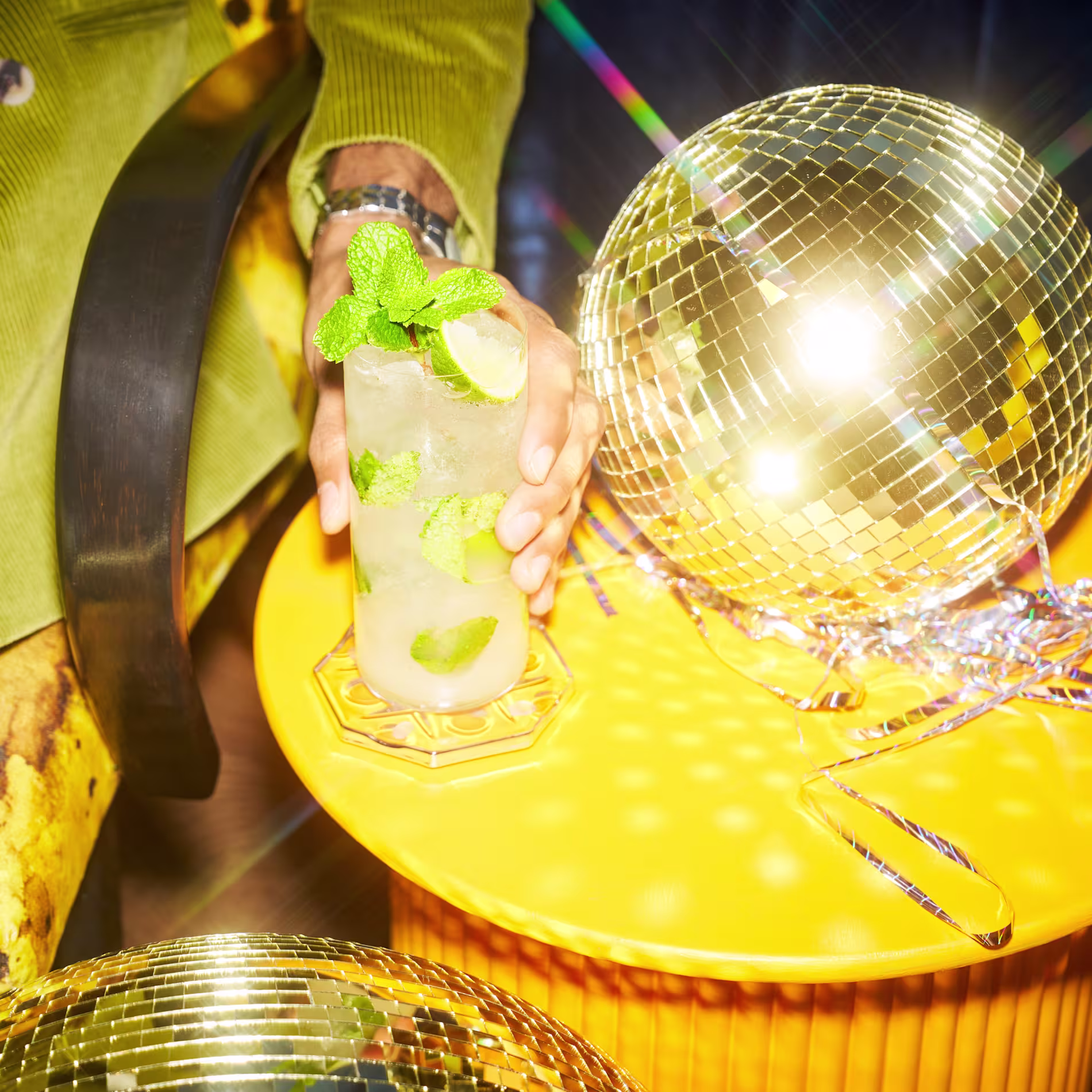 A mojito cocktail next to a disco ball