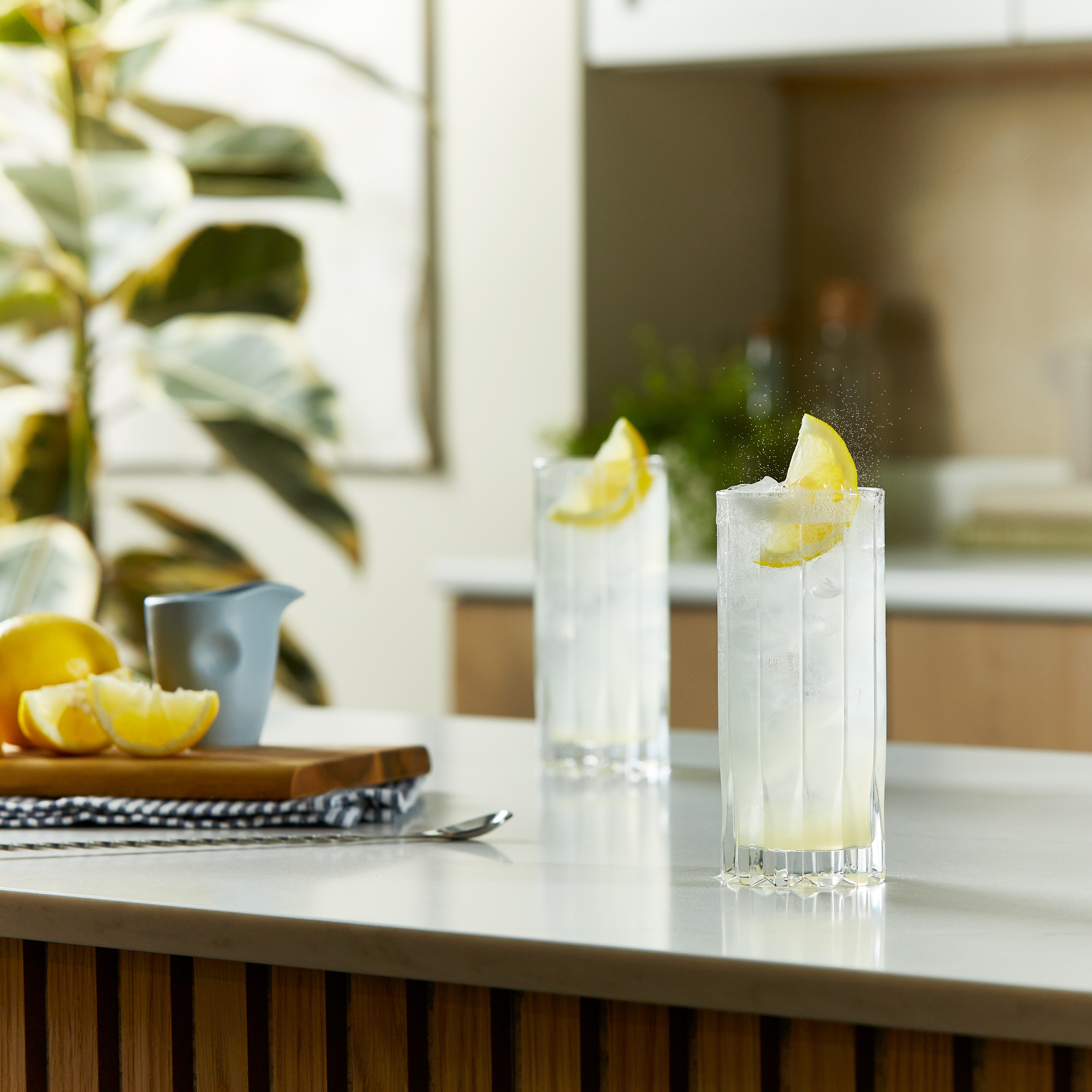 Două cocktailuri Tom Collins pe un blat de bucătărie.