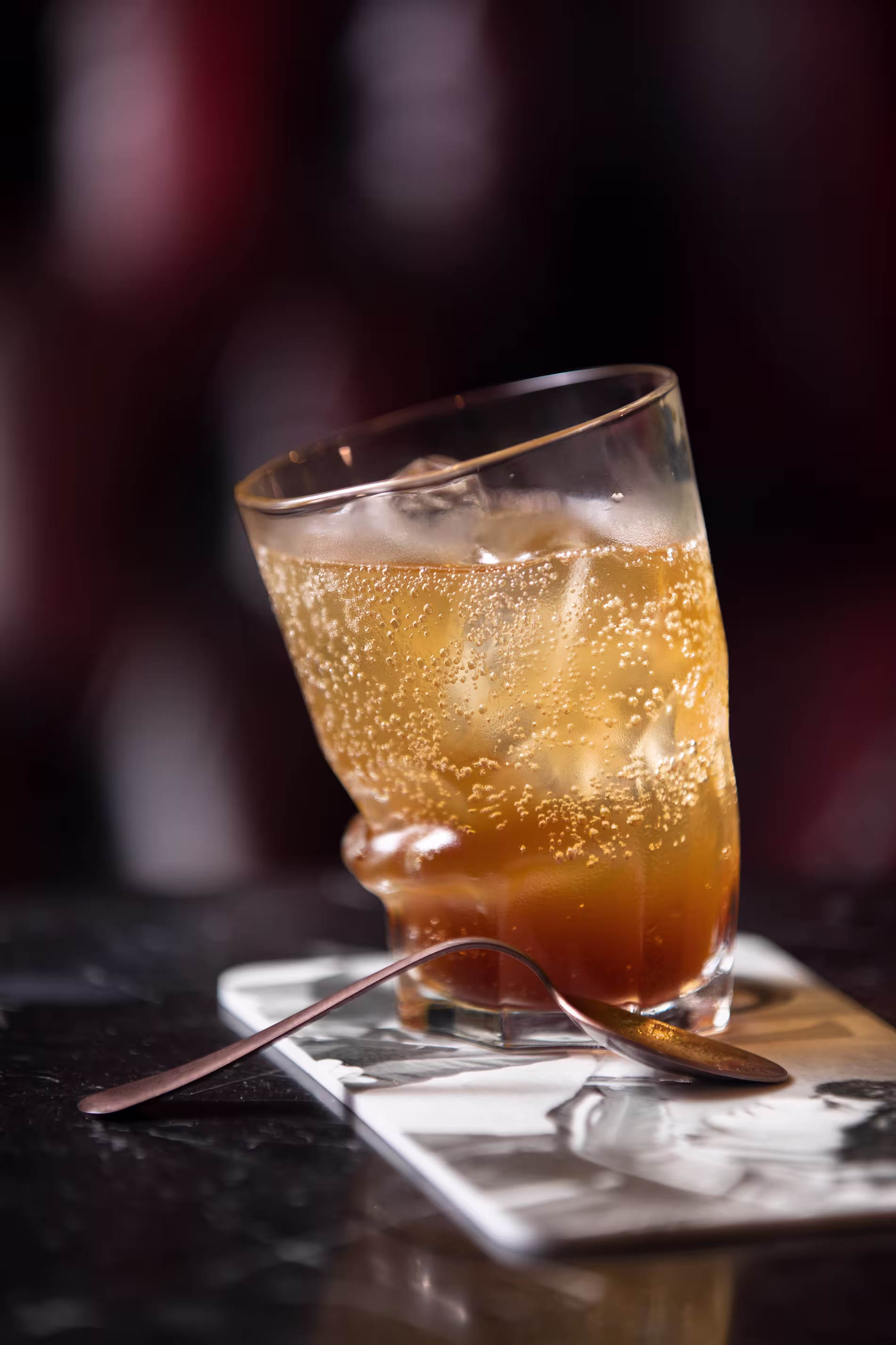 La imagen muestra el interior del Medium Club. Hay columnas altas, candelabros ornamentados y una barra bien surtida con varias botellas. La zona de asientos incluye taburetes altos a lo largo de la barra.
