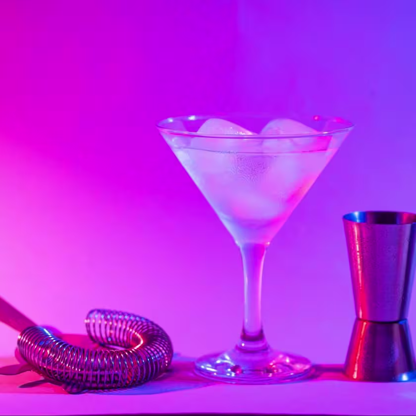 Una copa martini rodeada de elementos de coctelería.
