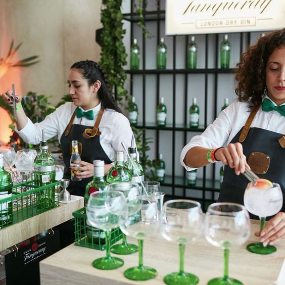Dos mujeres bar tender preparando Gin tonic con Tanqueray London Dry sobre una mesada 