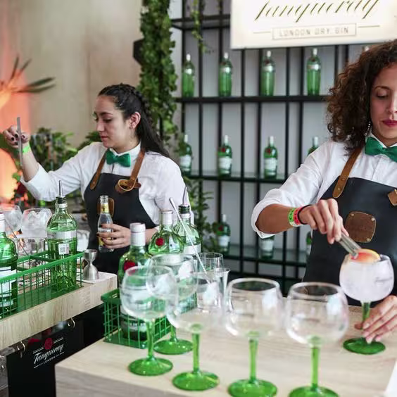 Dos mujeres bar tender preparando Gin tonic con Tanqueray London Dry sobre una mesada 