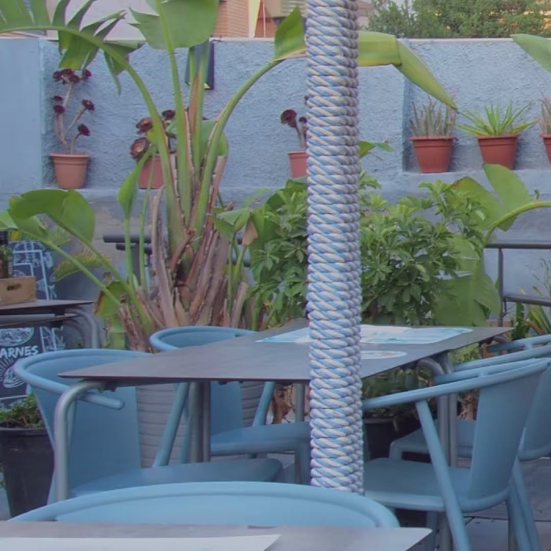 Un rincón lleno de frescura y encanto en la terraza de Restaurante Celeste, rodeado de vegetación y muebles azules que invitan a relajarse.