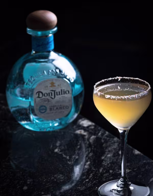 En la imagen se ve una botella de Don Julio Blanco, con un cóctel a su lado.