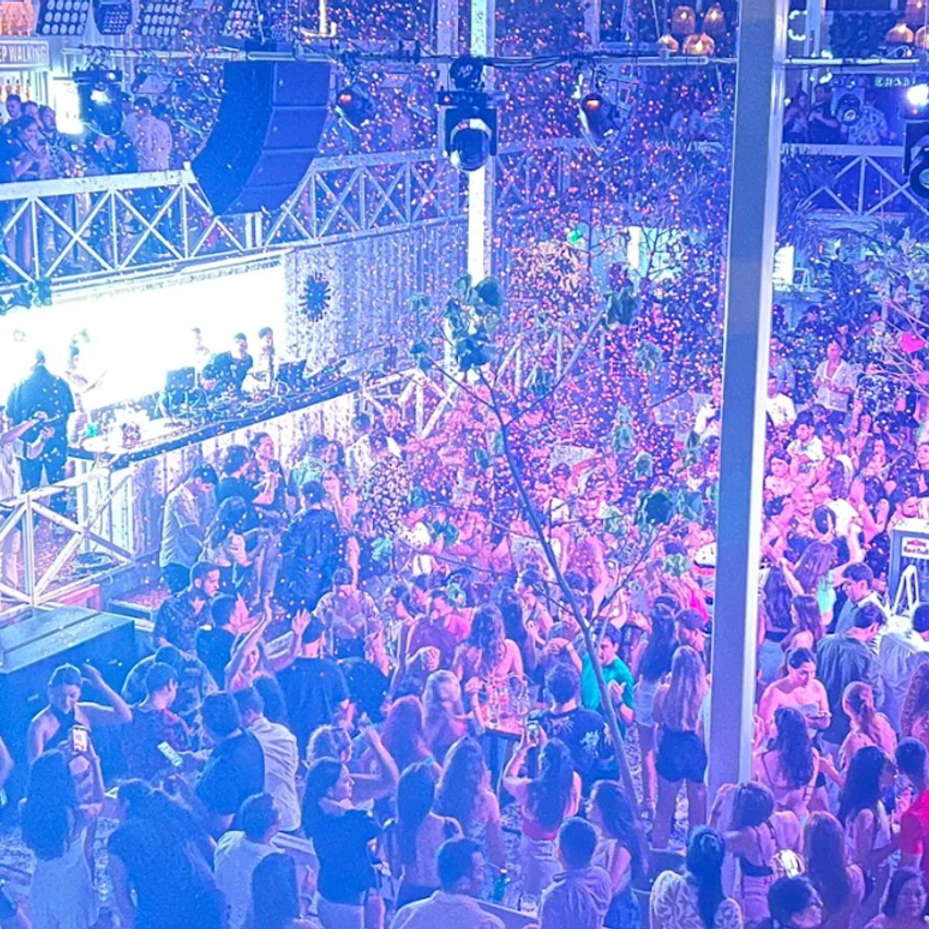 Imagen desde arriba de multitud de gente bailando. Cae papel de colores.