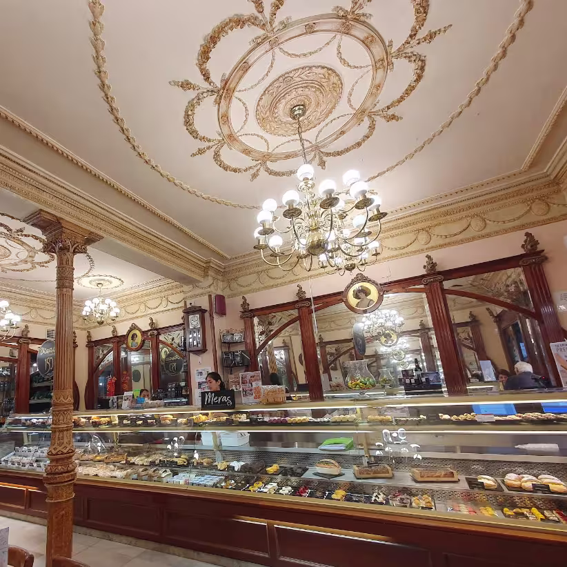 Techos ornamentados, lámparas de araña y vitrinas llenas de dulces en Viena Capellanes Goya. Un interior que respira tradición y elegancia.
