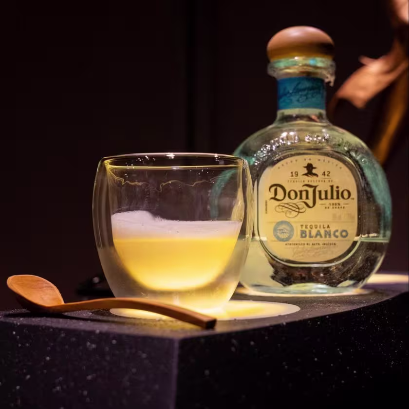 La imagen muestra una botella de tequila Don Julio Blanco junto a un vaso con un cóctel creado por el bartender finalista de World Class 2024 Perú, Joel Chirinos de Limaq.