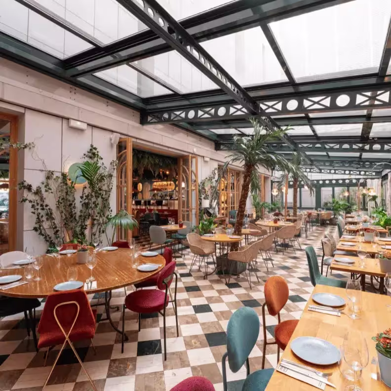 Un luminoso jardín interior con techos acristalados y vegetación exótica, Botania ofrece una experiencia culinaria rodeada de estilo y naturaleza.