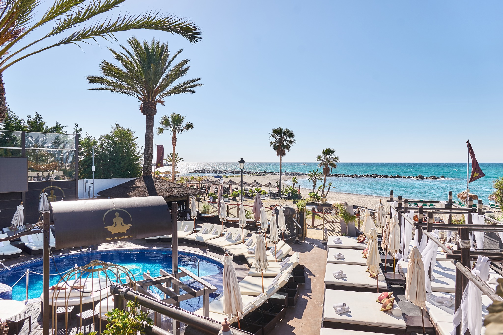 La Sala By The Sea presenta su piscina rodeada de camas balinesas y vistas impresionantes al mar Mediterráneo, ideal para un día de lujo.