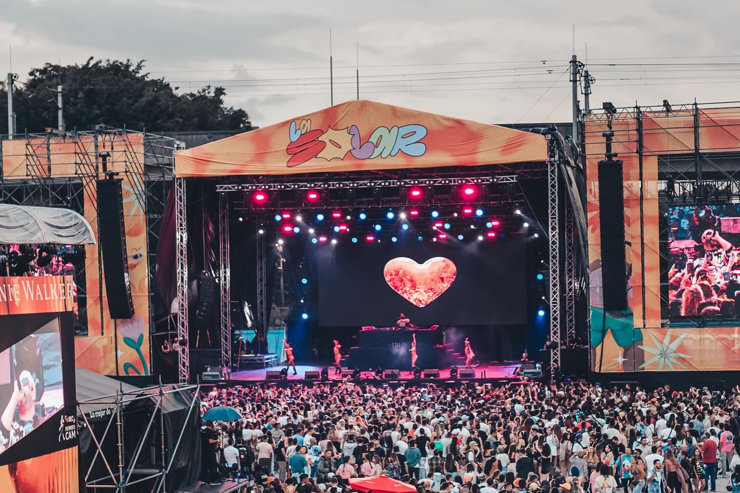 Un gran escenario en una fiesta multitudinaria con dj y bailarines en vivo.