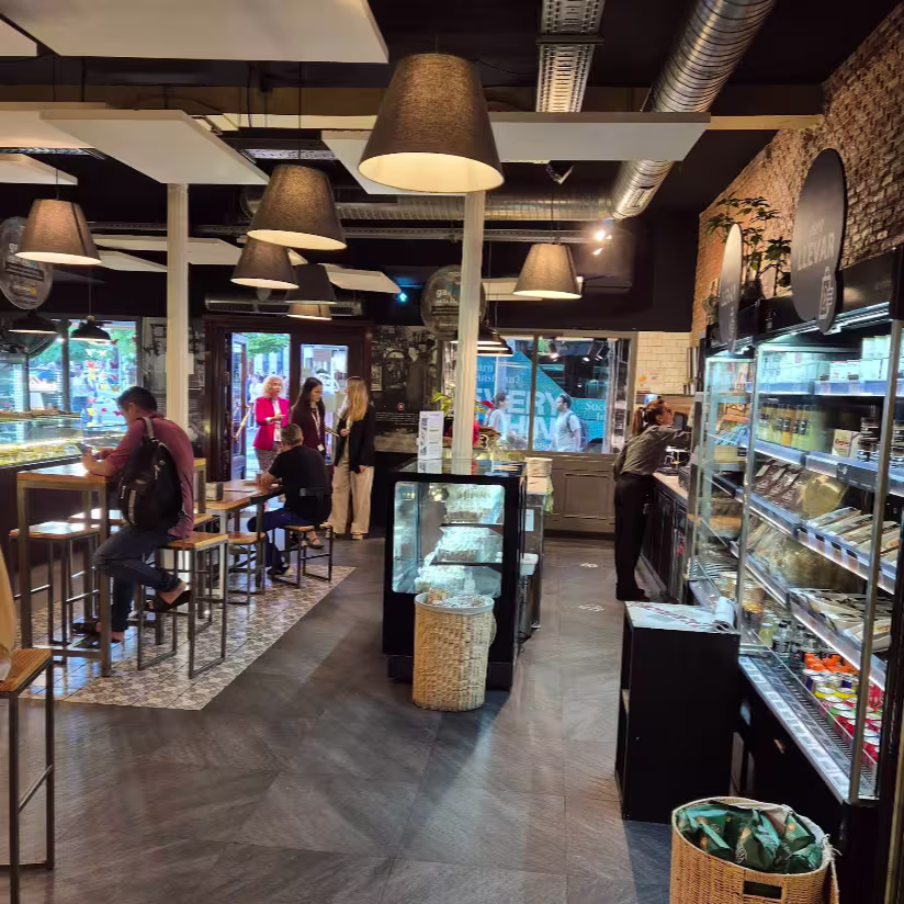 Interior moderno y funcional de Viena Capellanes Génova, con zona de refrigerados, mesas altas y luz cálida que invita a una pausa cómoda y rápida.