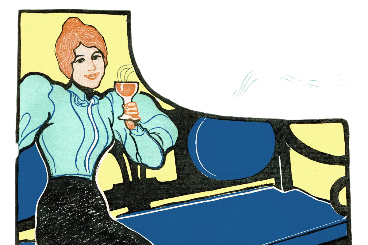 A woman with red hair in a blue blouse sits on a blue and black bench, holding a glass, against a plain light background.
