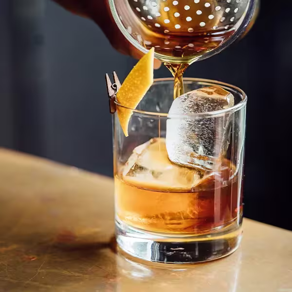 Pouring Scotch into a glass with ice.