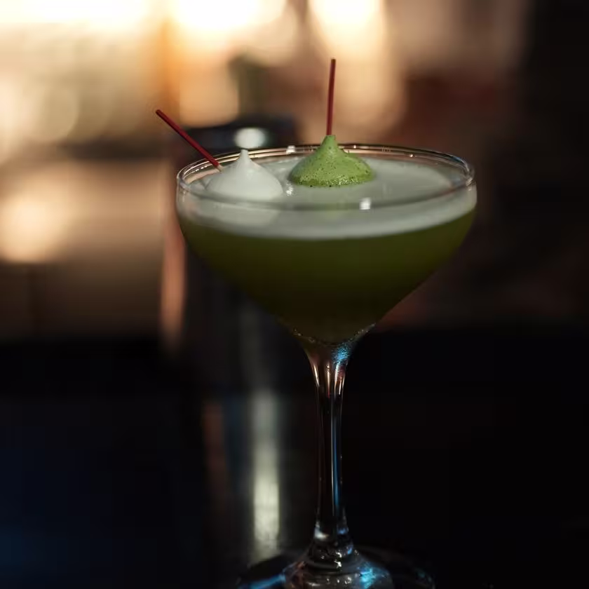 Un cóctel color verdoso servido en una copa de martini en el evento de Clase Maestra.
