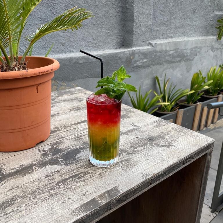En Restaurante Celeste, cócteles vibrantes como este destacan en su terraza urbana, rodeada de plantas y un estilo relajado.