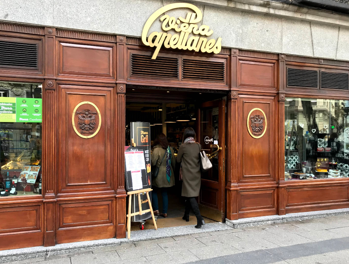 Fachada de madera noble en Viena Capellanes Génova, con escaparates clásicos y ambiente acogedor que invita a entrar desde la calle.