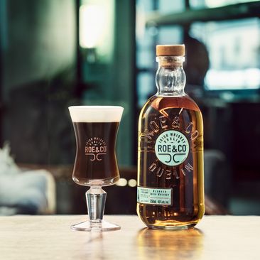 Bottle of Roe & Co Irish whiskey next to an Irish Coffee cocktail
