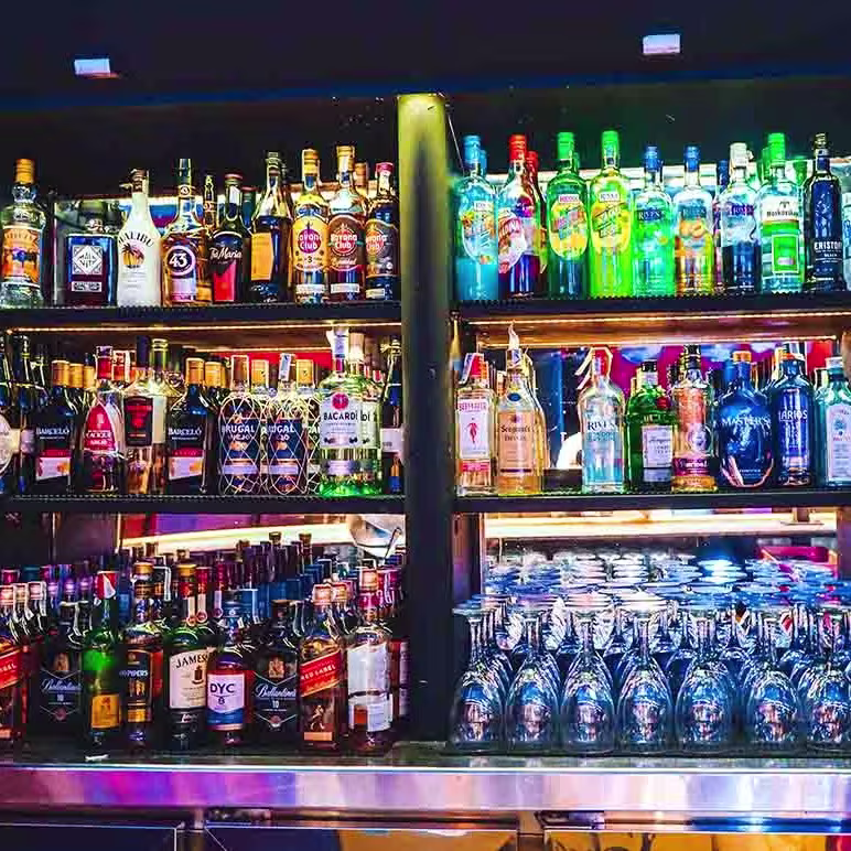 Voulezbar presenta una barra vibrante con una amplia selección de licores y cócteles, destacando su iluminación moderna y ambiente dinámico.
