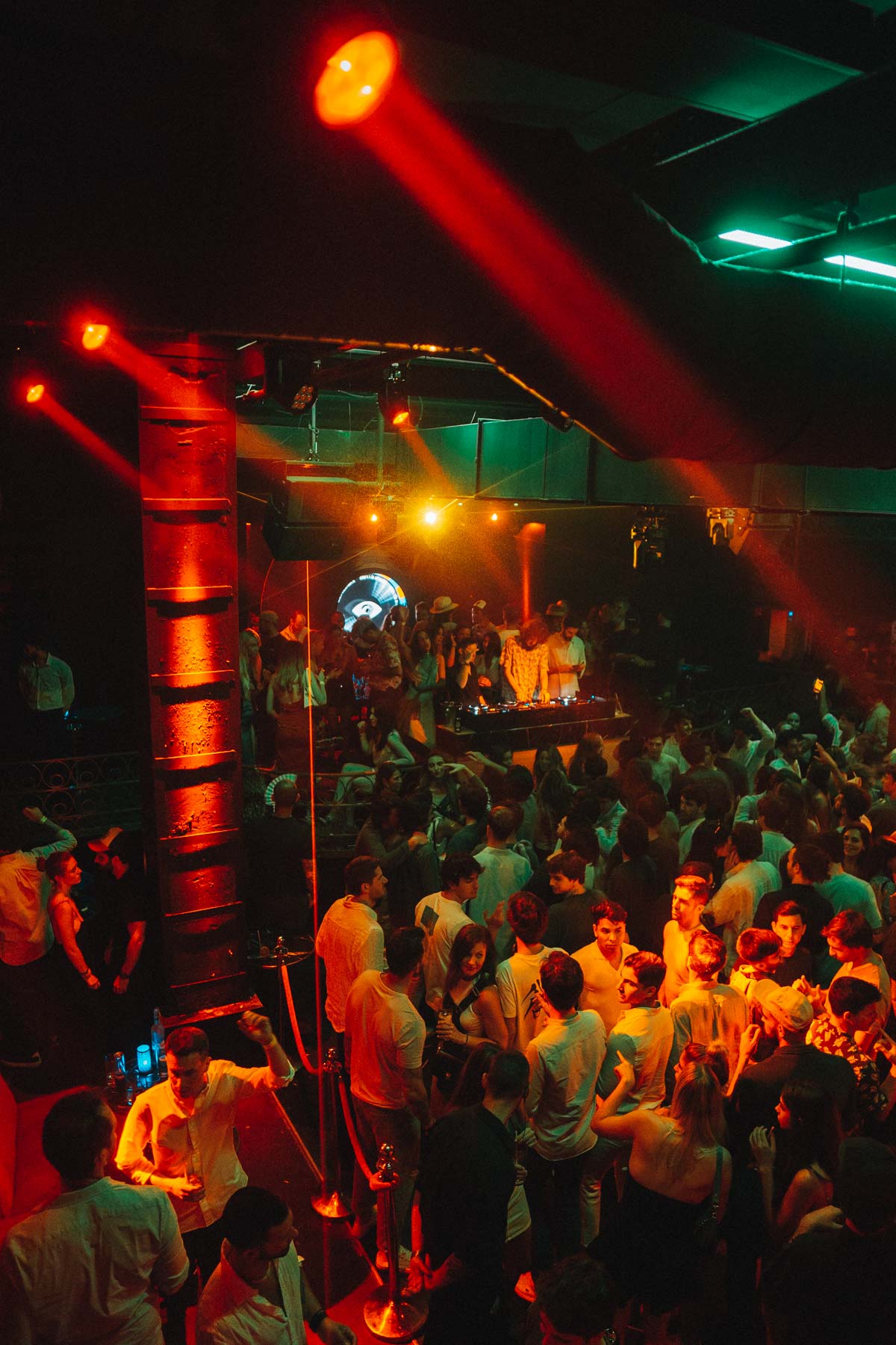 Interior de Lula Club durante una noche vibrante, con luces cálidas y una multitud disfrutando de la música en directo frente a la cabina del DJ.