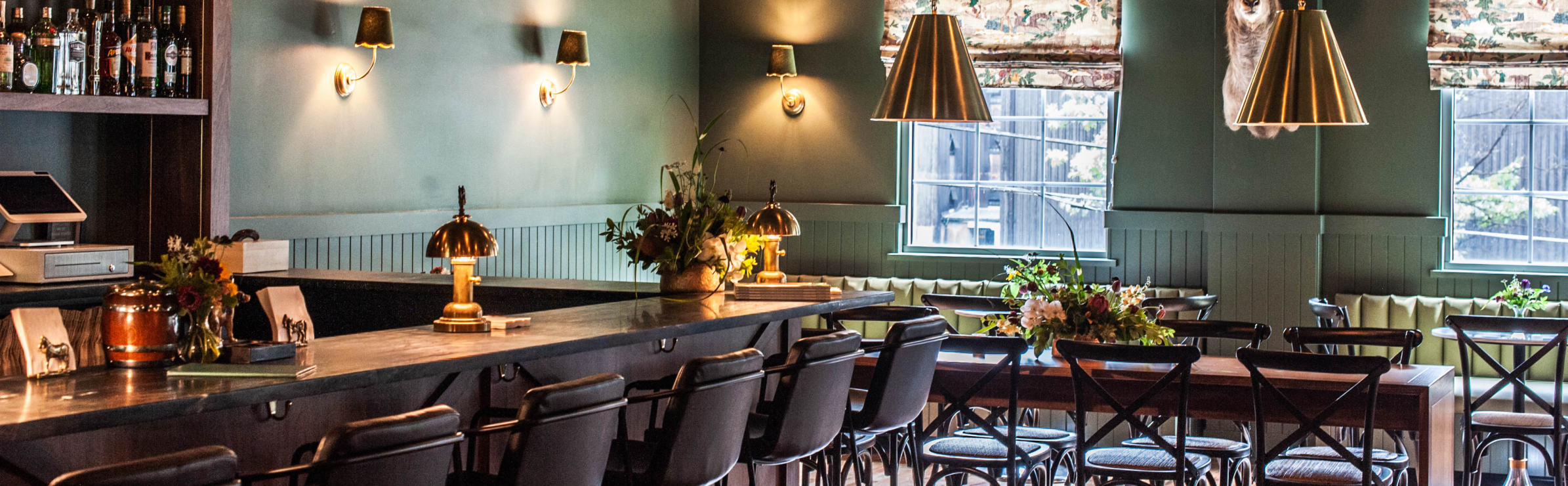 Interior of the Garden & Gun Club restaurant inside Stitzel-Weller Distillery with green chairs and wood tables.