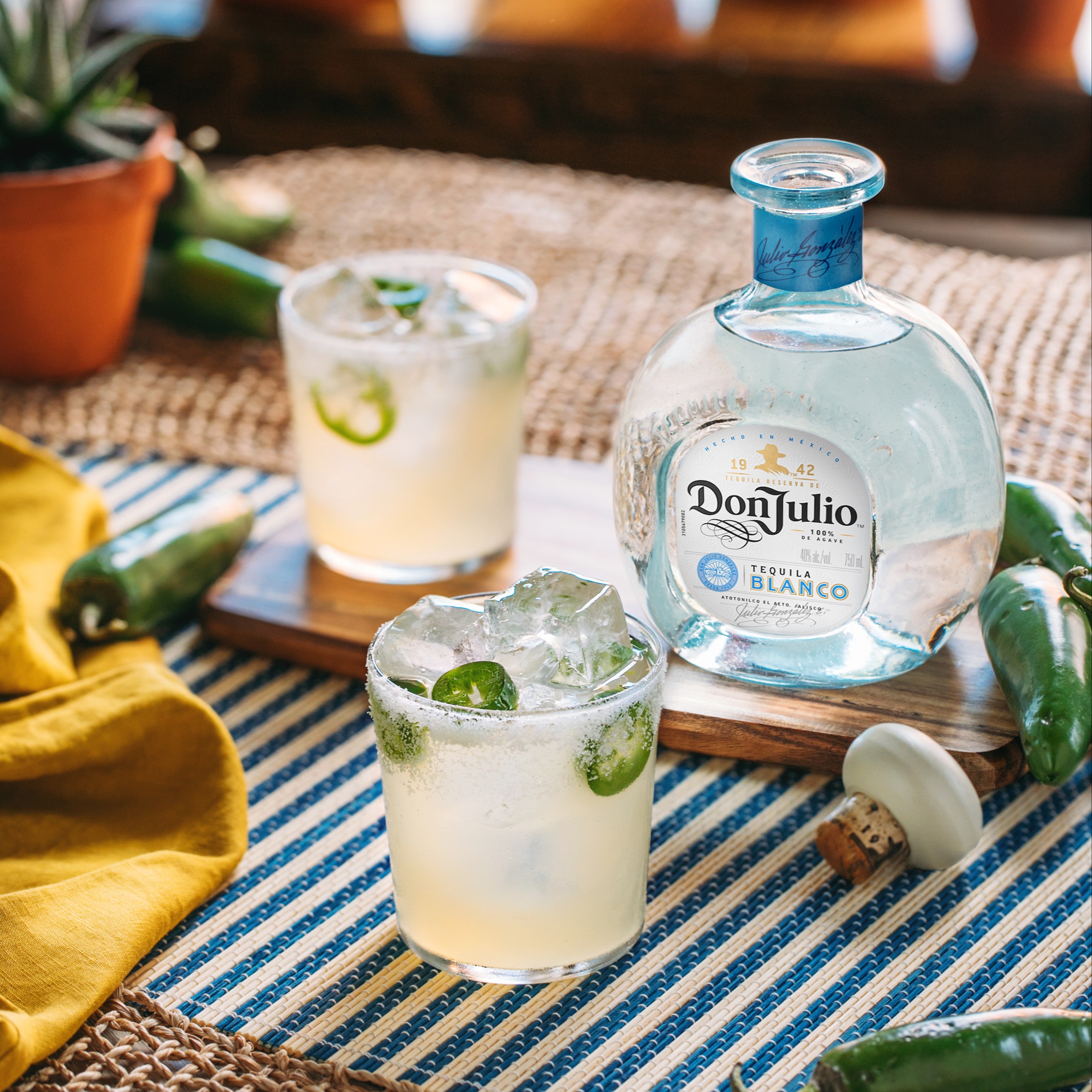 Glass of Don Julio spicy margarita on a striped tablecloth. 