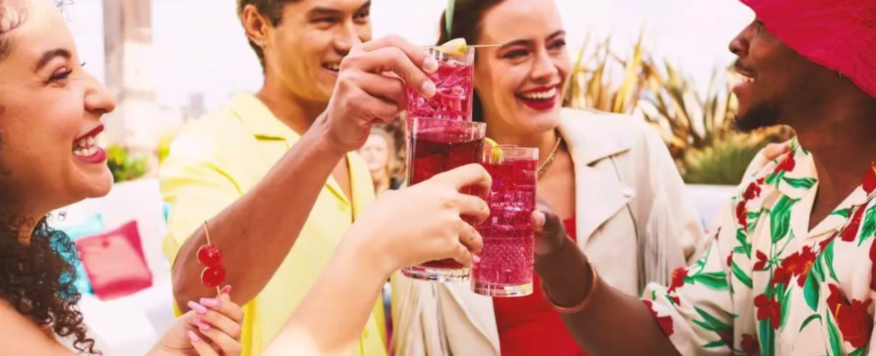 La imagen muestra cuatro personas brindando con vasos que contienen cócteles preparados con vodka Smirnoff.