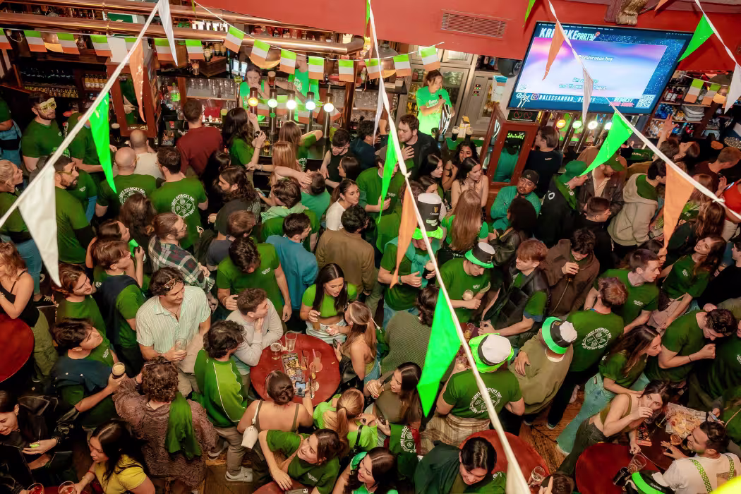 La imagen muestra una gran figura inflable con una cara sonriente, que lleva un sombrero y traje verde, posiblemente relacionado con las celebraciones del Día de San Patricio. 